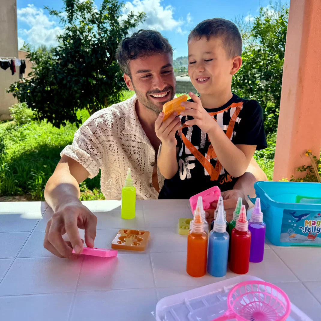 A child working steadily at a table covered in finished colorful figures